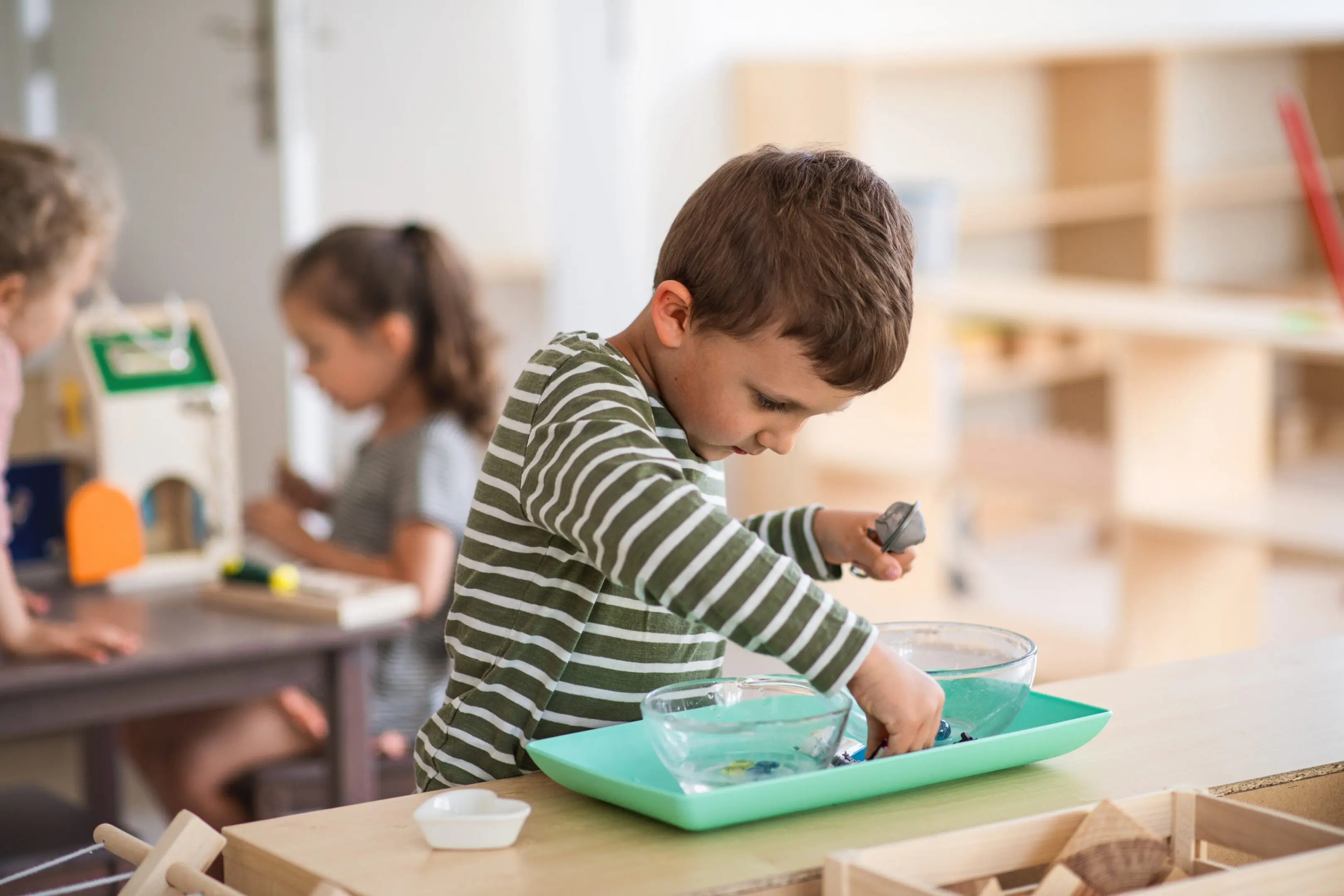Child playing with water at a table.