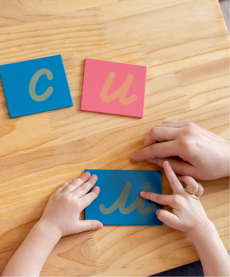 Child learning letters with adult guidance.