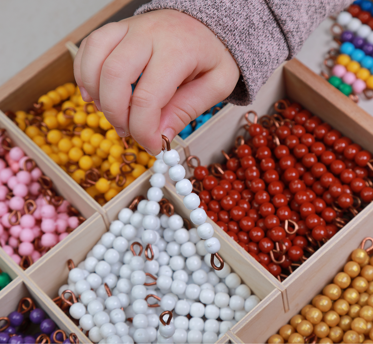Child's hand holding colorful beaded strings.